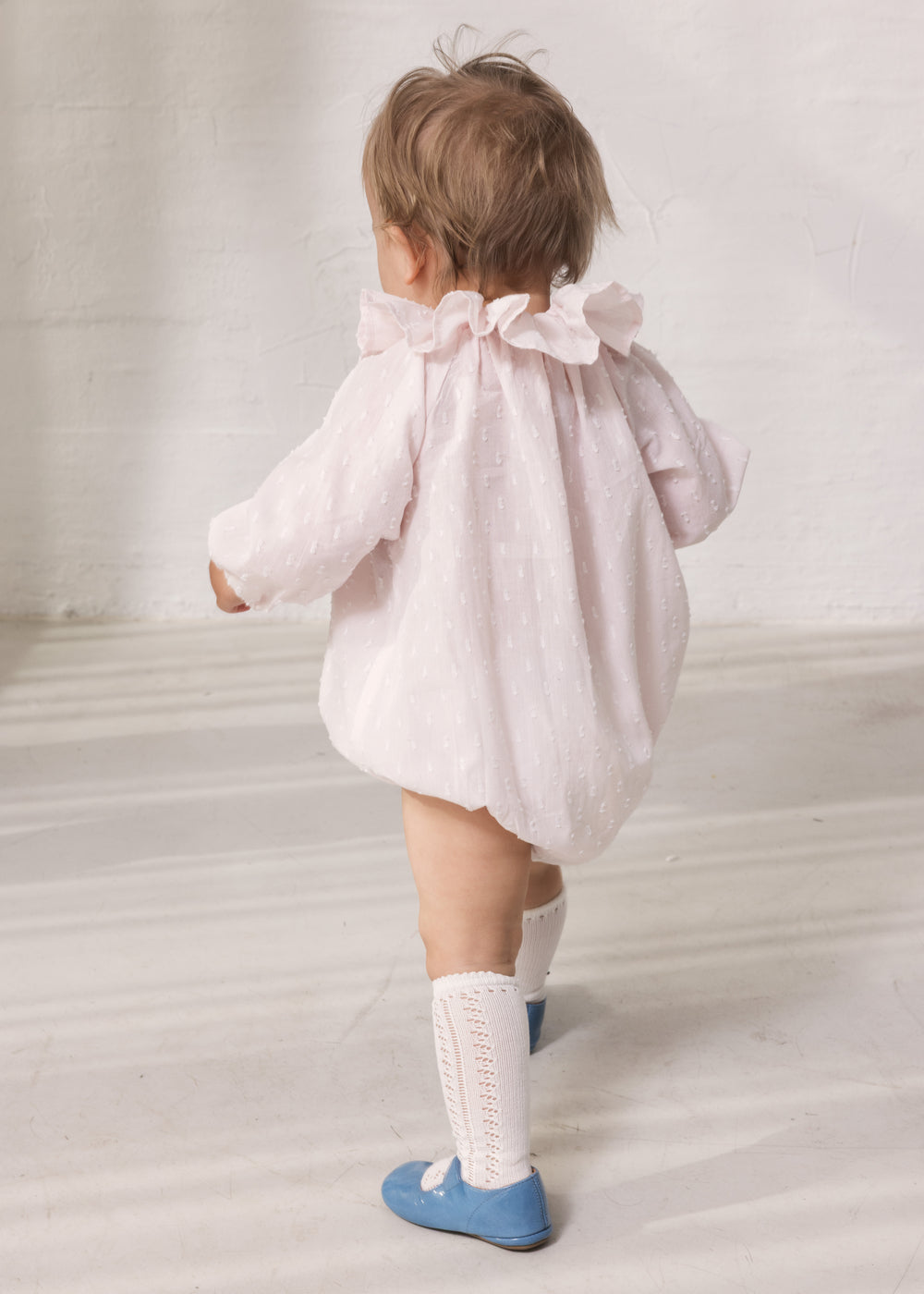 Baby wearing a bright red dress with long sleeves and a peter pan collar.