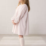 Child wearing a bright red dress with a loose fit.