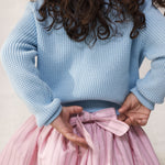 Wearing a blue striped sweater and a bright red skirt.