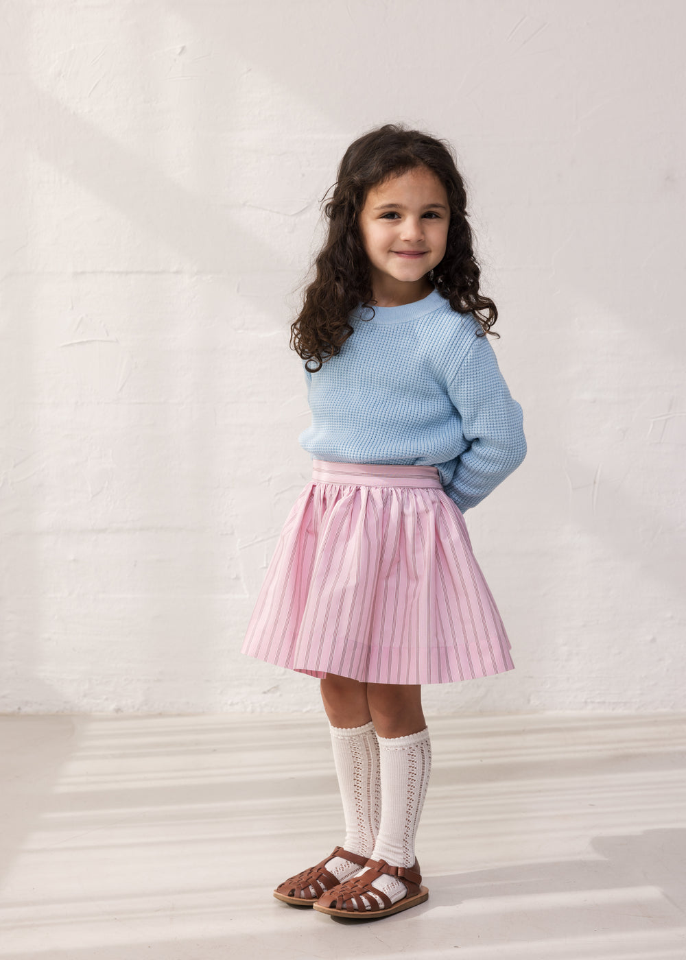 Wearing a blue striped sweater and a bright red skirt.