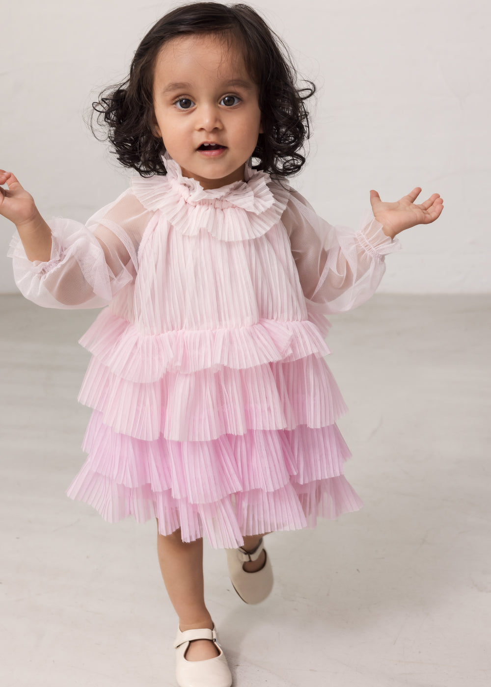 Wearing a bright red long-sleeved baby dress in pleated tulle with multiple layers.
