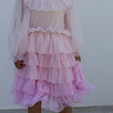 Children wearing a bright red long-sleeved dress in pleated fabric with multiple layers.