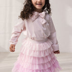 Wearing a red skirt in light, pleated tulle with multiple layers and a blouse.