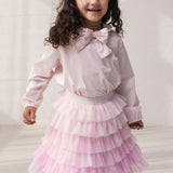 Wearing a red skirt in light, pleated tulle with multiple layers and a blouse.