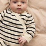 Baby wearing a striped cardigan with stripes and toggle closure, matching pants and hat.