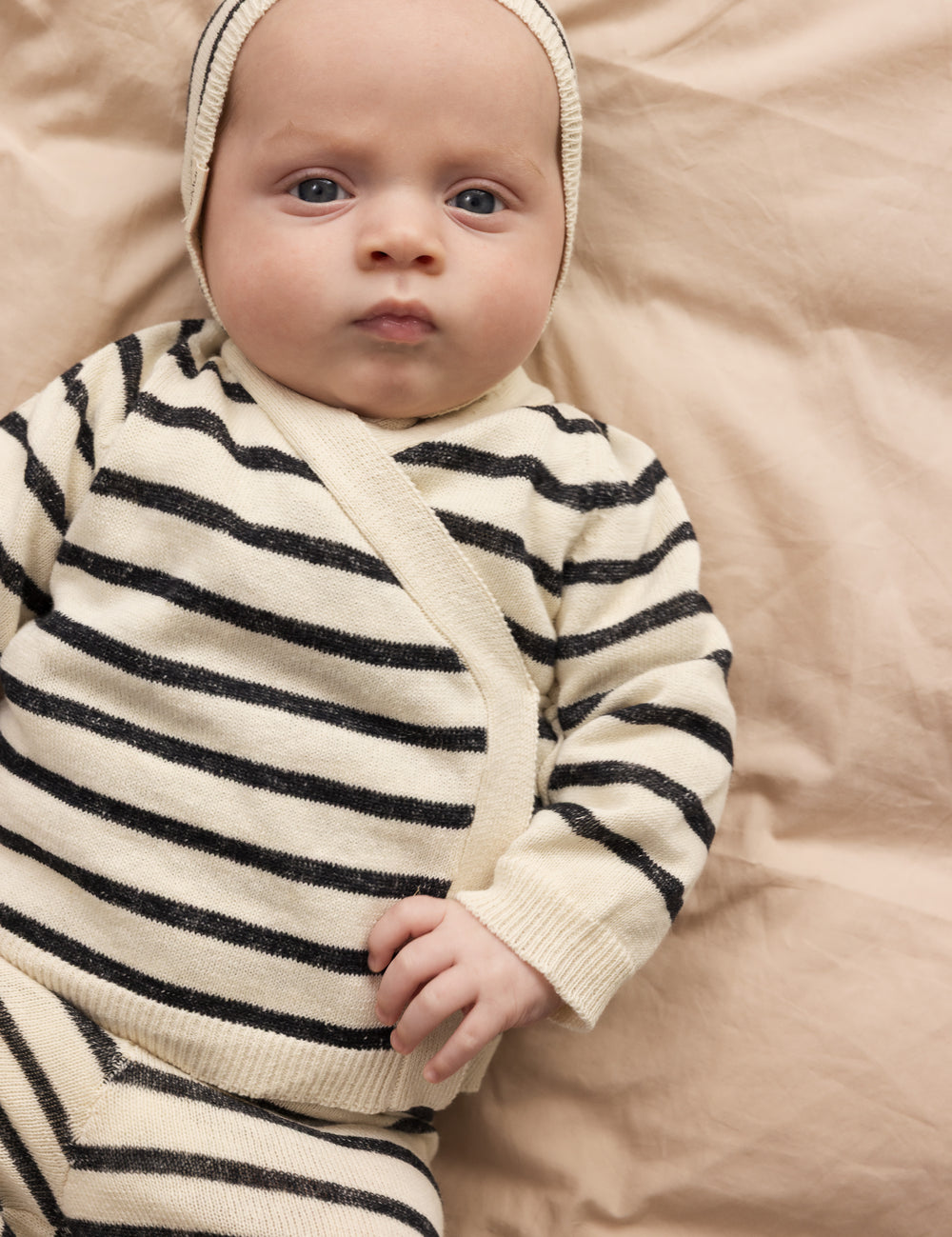 Baby wearing a striped sweater and matching baby helmet.