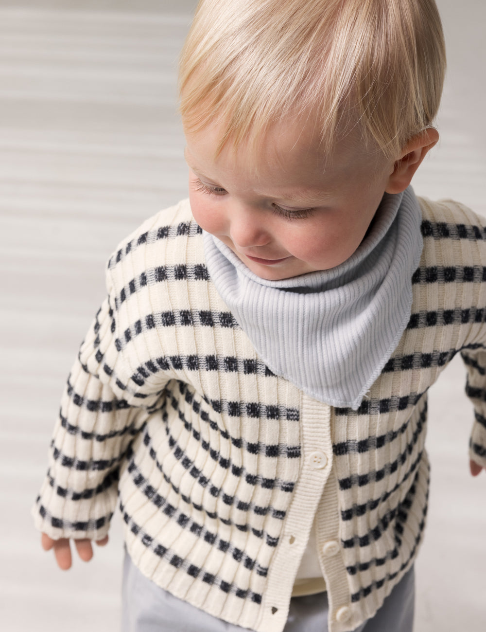 Baby worn striped cardigan with round neck, stripes, and button-up closure.