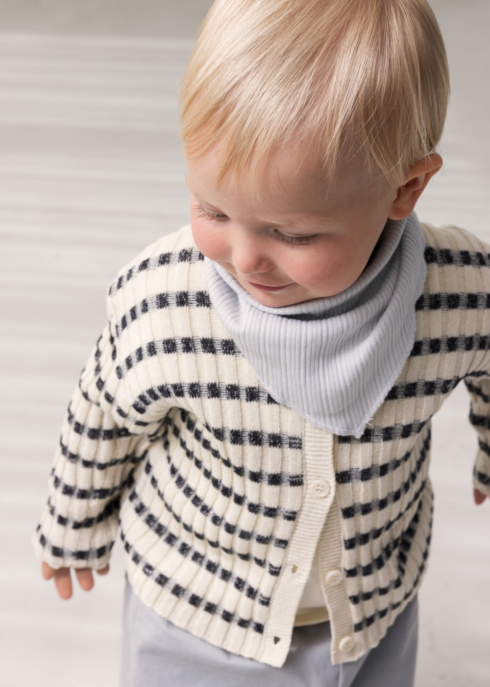 Baby worn striped cardigan with round neck, stripes, and button-up closure.