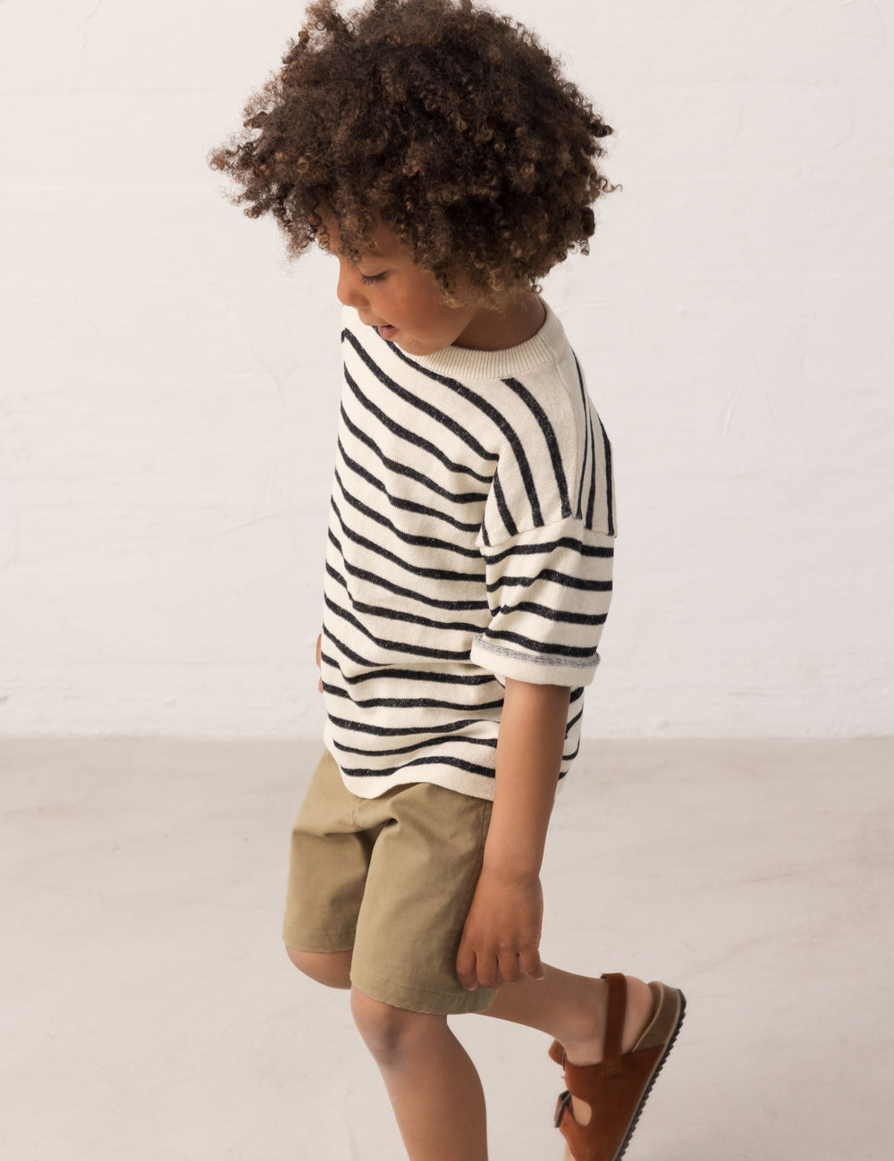 Children wearing a striped shirt and green shorts set from the side