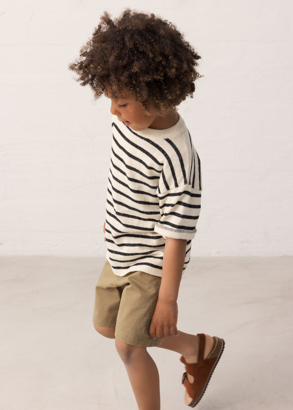 Children wearing a striped shirt and green shorts set from the side
