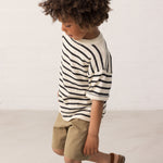 Children wearing a striped shirt and green shorts set from the side