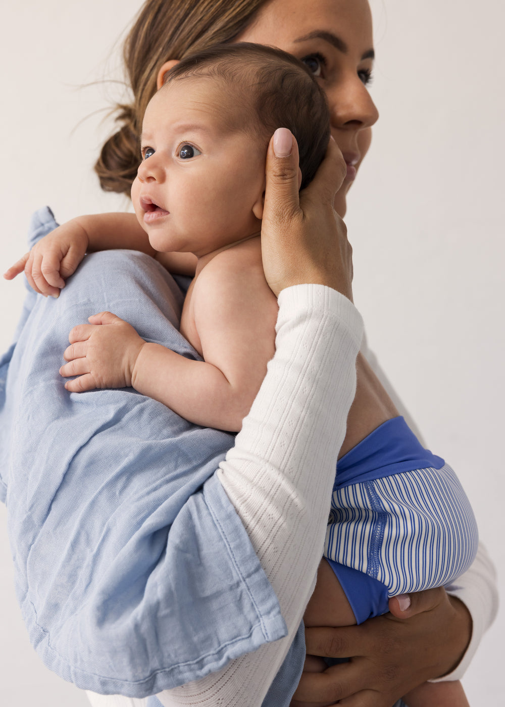 Baby held by a woman with fabric around her body.