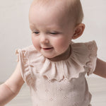 Baby wearing short-sleeved bright red knitted bodystocking with hole pattern and ruffled collar.