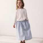 Wearing a light blue skirt and a white cardigan.