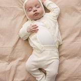 Baby wearing a raw white helmet and matching matching helmet.