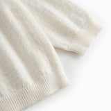 White striped cardigan for baby, with a pretty hole pattern and button closure.