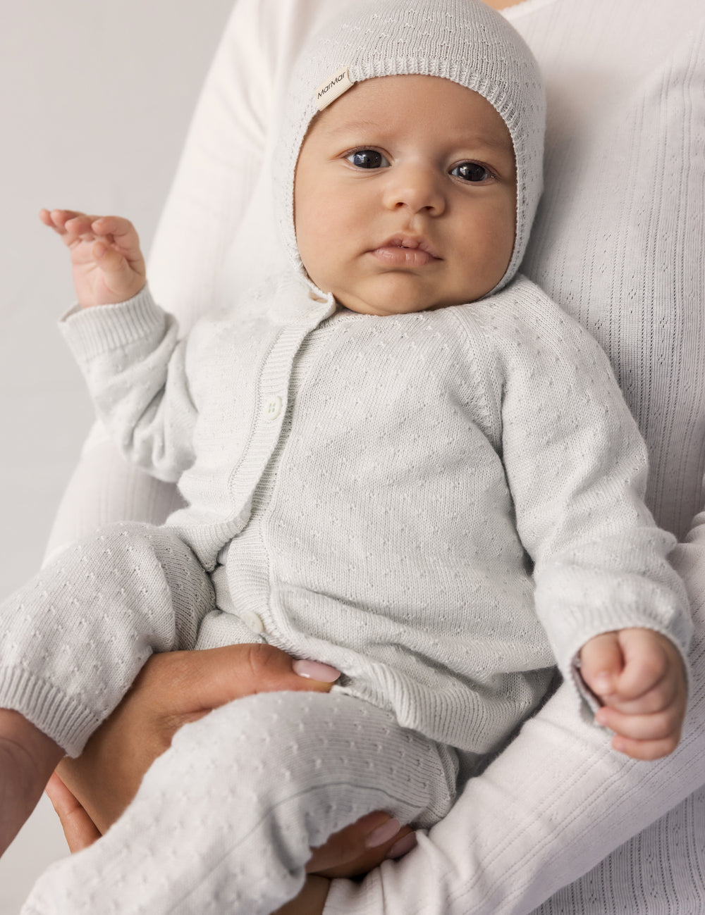 Baby wearing a light green striped cardigan, matching pants and hat.