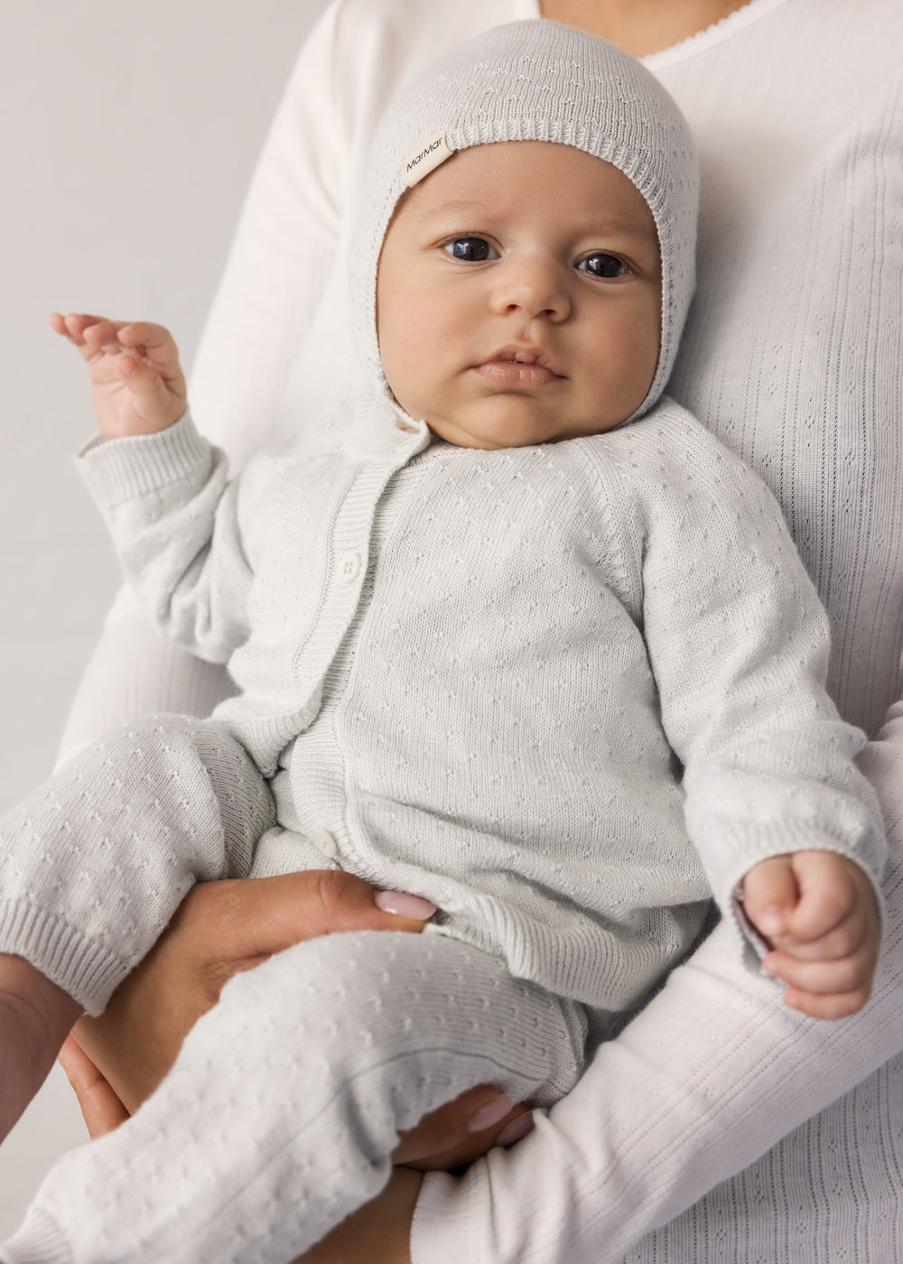 Baby wearing a light green striped cardigan, matching pants and hat.