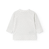 Hvid babybluse med slå-om lukning og fint mønster