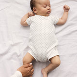 Baby sleeping in white footless sleepsuit with fine pattern