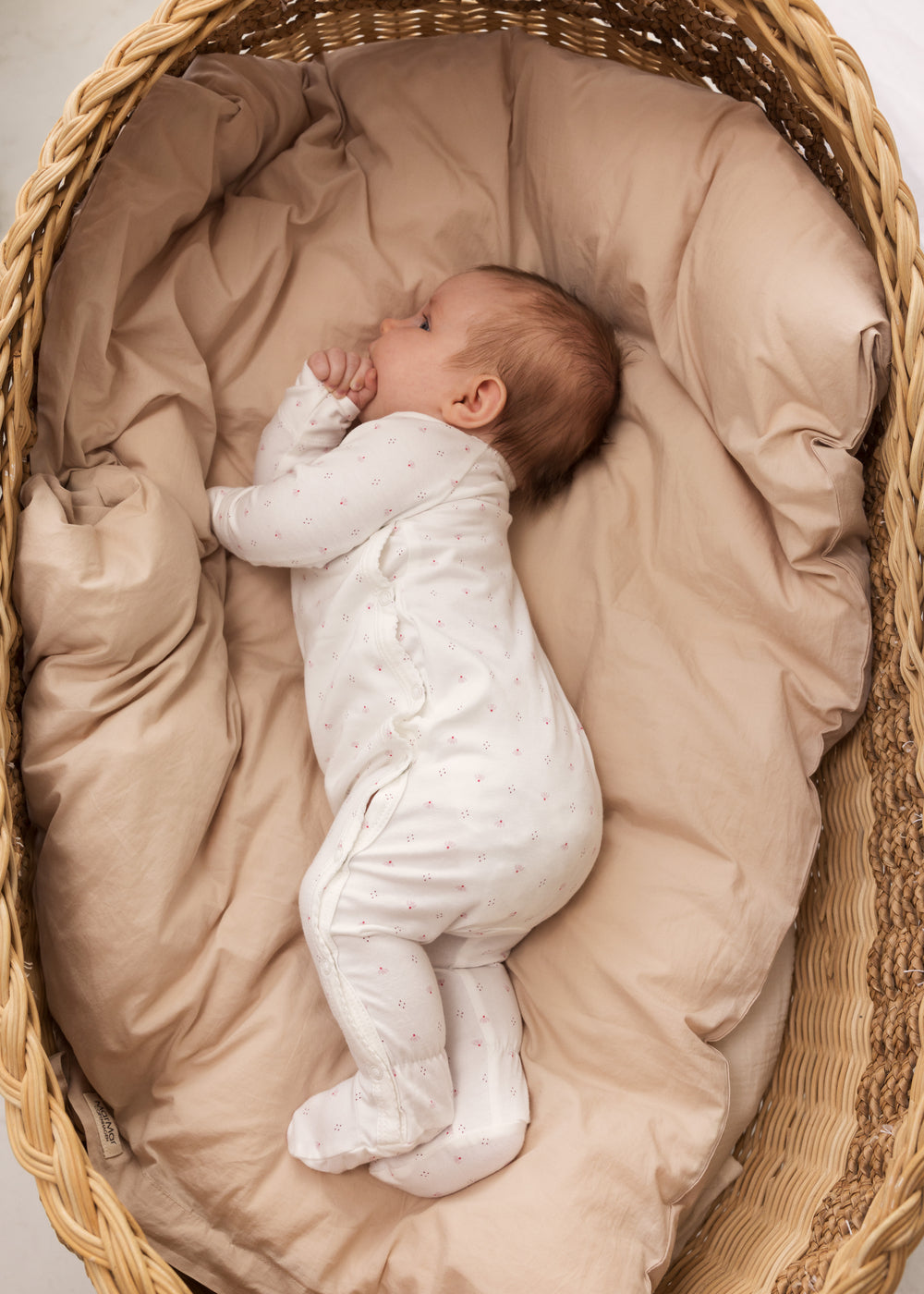 baby in white full-body suit with feet in fine floral pattern