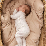 baby in white full-body suit with feet in fine floral pattern