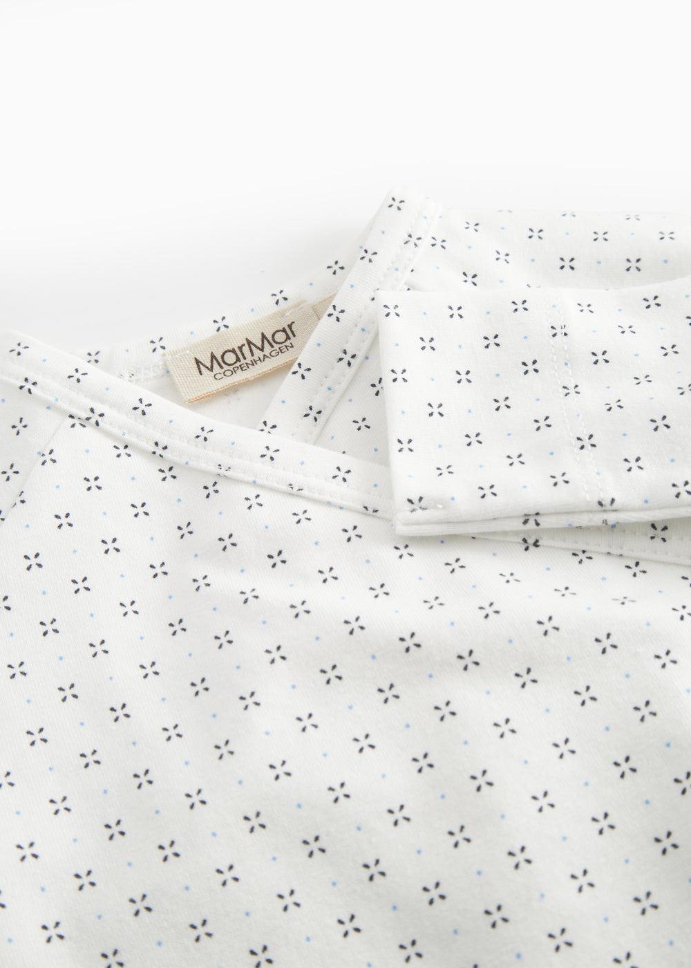 White baby all-in-one with wrap-around closure and a fine pattern