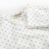 White baby all-in-one with wrap-around closure and a fine pattern