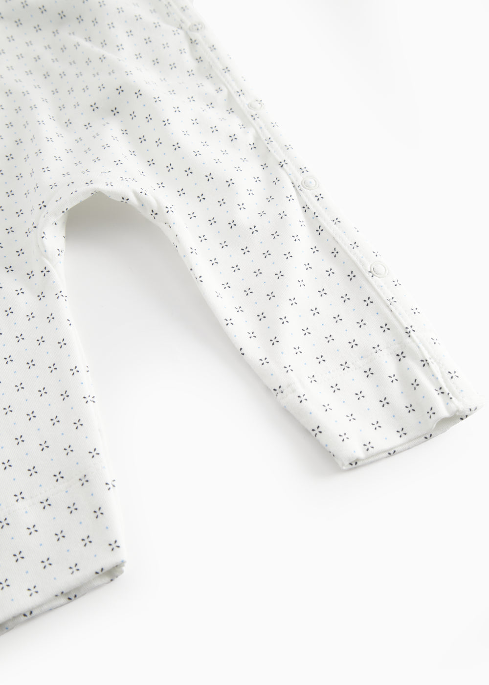 White baby all-in-one with wrap-around closure and a fine pattern