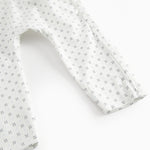 White baby all-in-one with wrap-around closure and a fine pattern