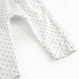 White baby all-in-one with wrap-around closure and a fine pattern