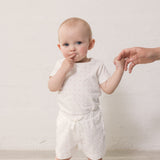 Baby in white shorts and bodysuit with small flowers