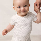 Baby in white short-sleeved bodysuit with fine pattern