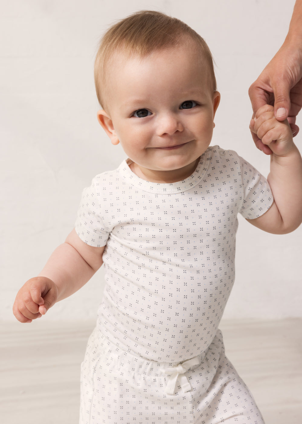 Baby in white shorts and bodysuit with fine pattern