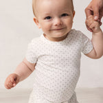 Baby in white shorts and bodysuit with fine pattern