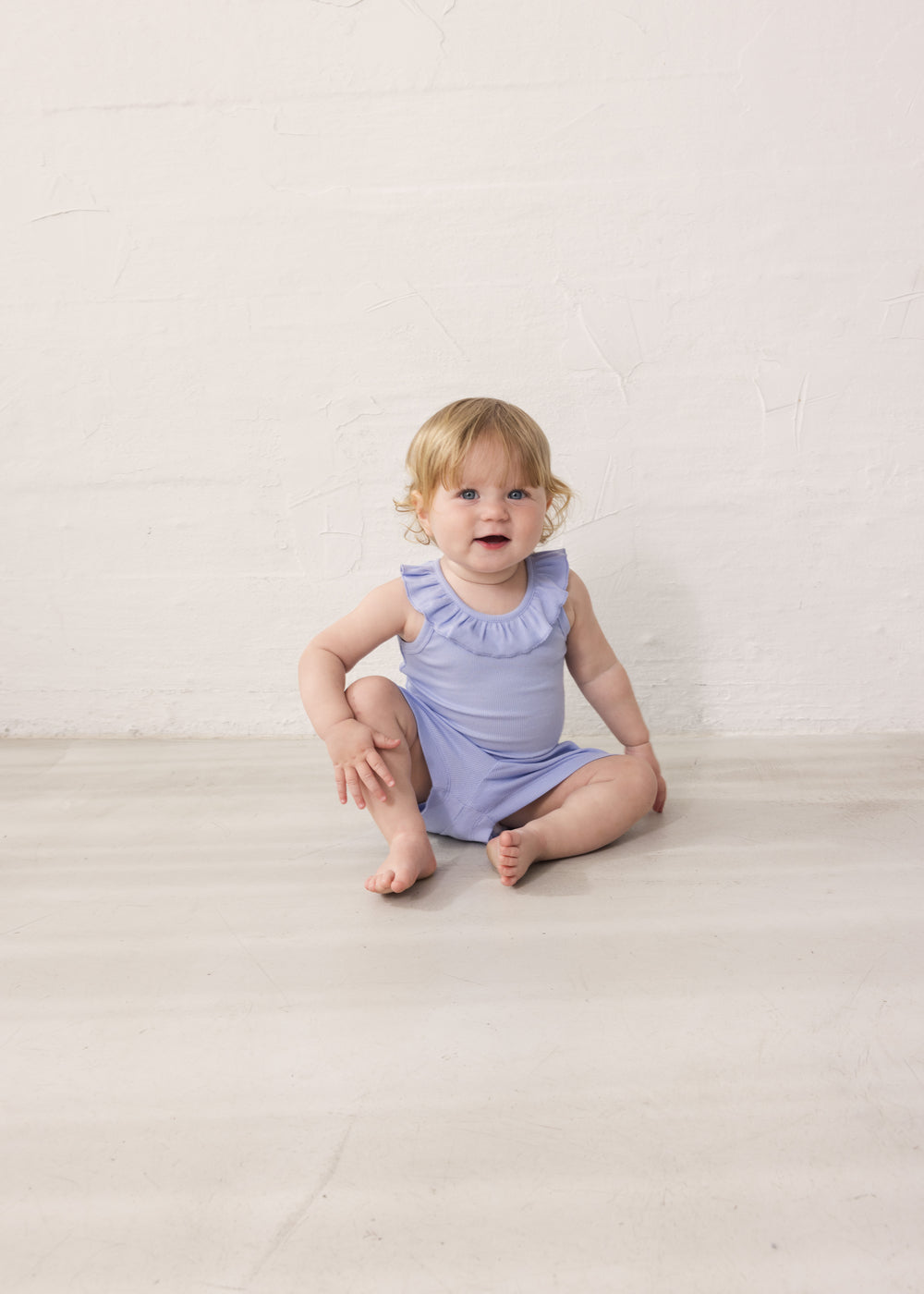 Baby in light purple bodysuit with ruffle collar