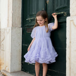 Pige der står i en lyselilla tylkjole foran en grøn dør