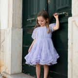 Pige der står i en lyselilla tylkjole foran en grøn dør