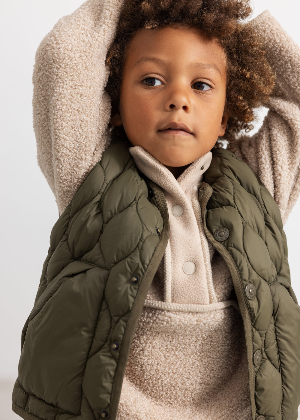 Teddy parka in olive green with quilted front, snap button closure and beige fleece hood.