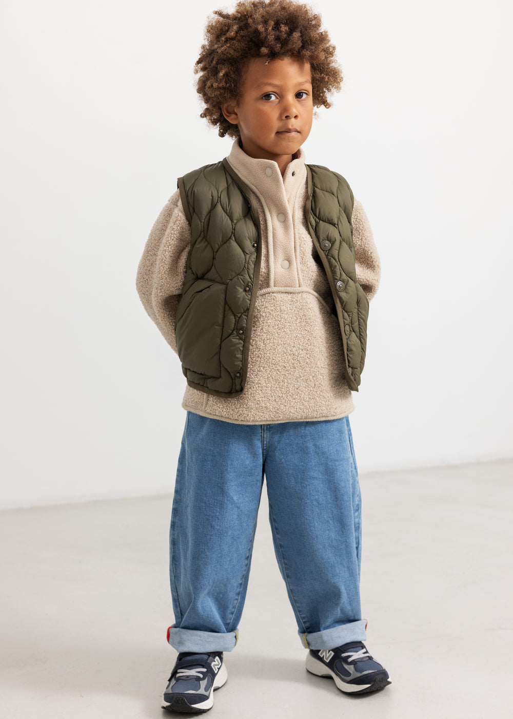 Olive green teddy parka with quilted pattern and beige fleece hood, snap buttons in front.