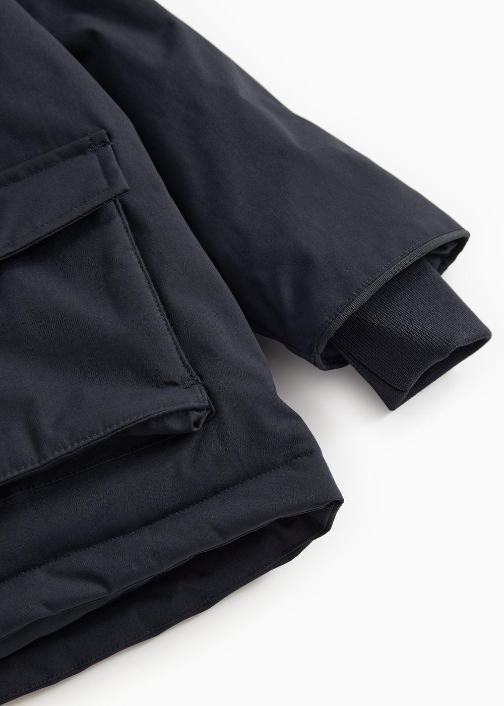 Winter jacket in dark navy with ribbed cuff and slanted seam at the bottom.