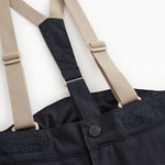 Details: dark cover pants with beige suspenders and a round button at the waist.