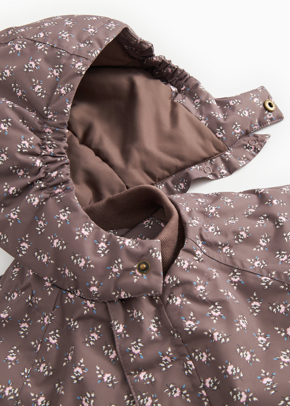 Jacket with open zipper and lined interior; small floral print in dark brown.