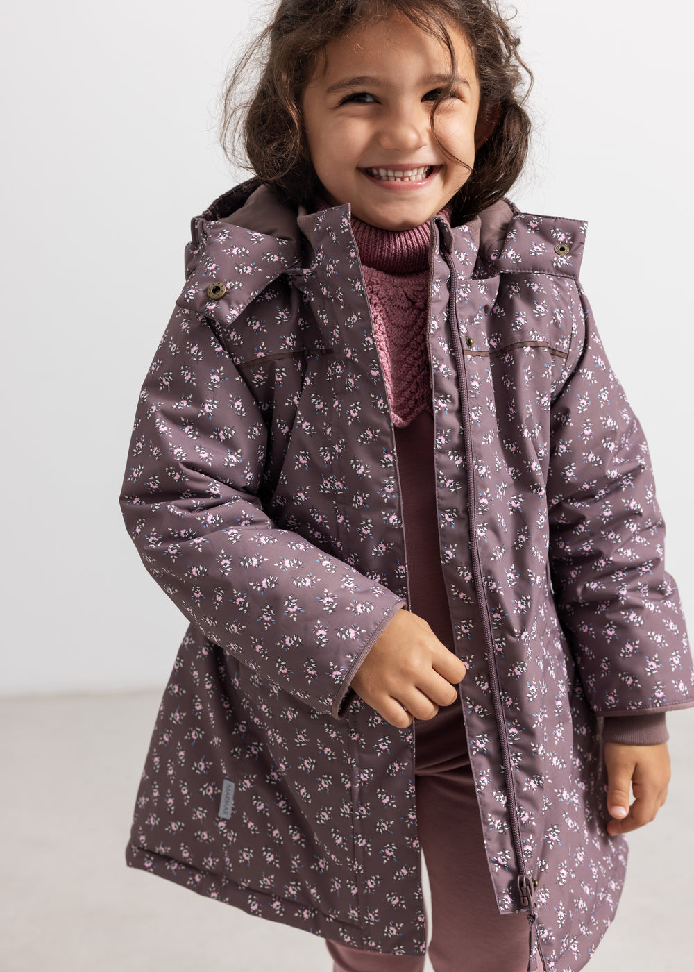 Kids winter jacket with hood, zipper and floral pattern in dark purple and pink.
