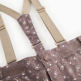 Tight-fitting trousers: suspenders with metal ring and dark brown floral print.