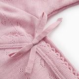 Pink baby jumpsuit with a bow at the chest and a finely dotted embroidery structure.
