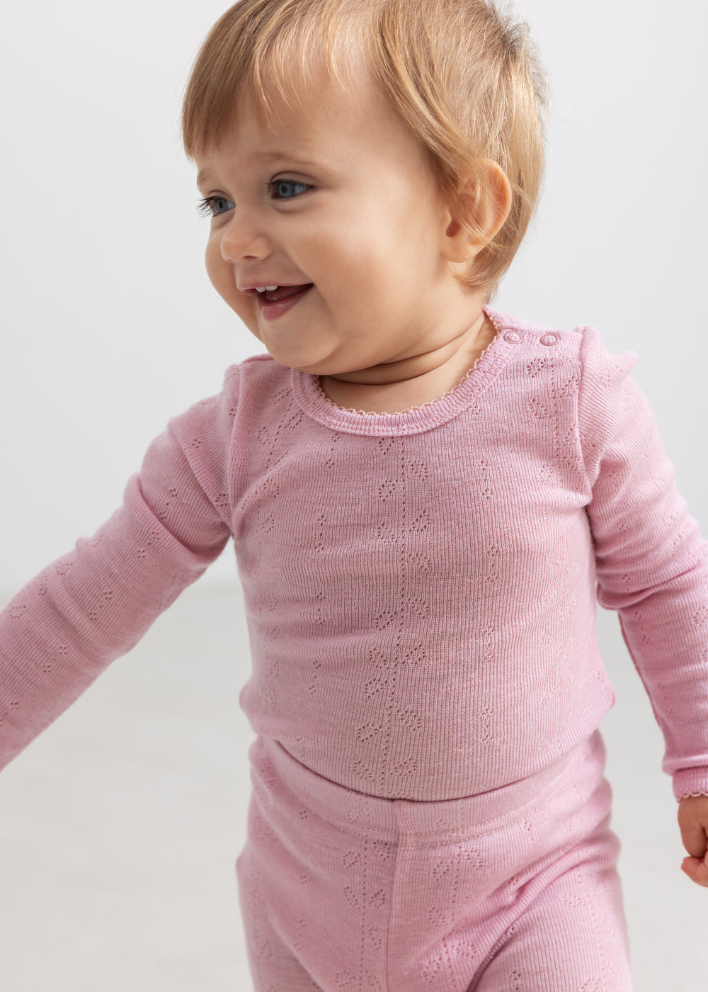 Pink bodystocking with long sleeves and a finely perforated texture for the child.