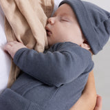 Born in a dark gray ribbed knit hat, eyes closed, hands on the face.