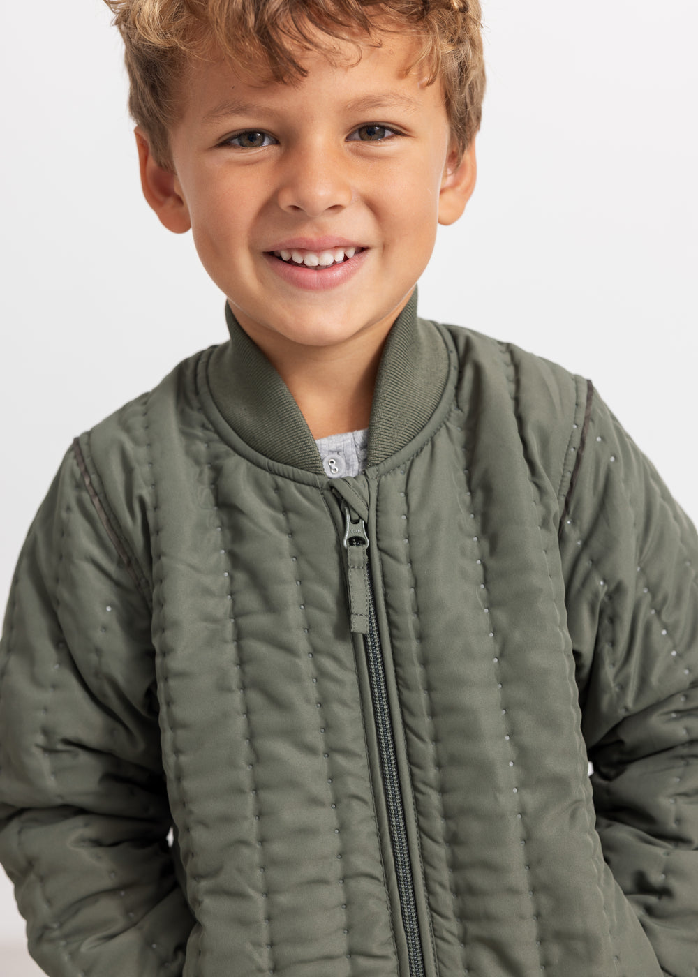 Green quilted down jacket for children with full zipper and stand-up collar.