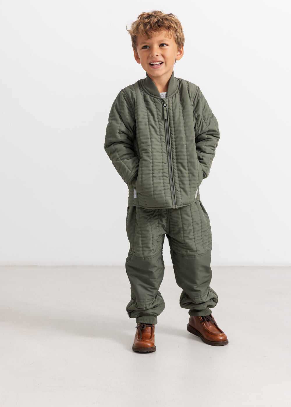 Green jacket for children with visible front zipper and padded sections.